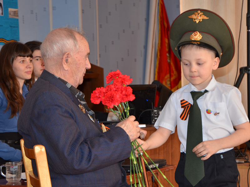 Ученик 1 «В» класса вручает цветы ветерану Николаю Тимофеевичу Новгородову
