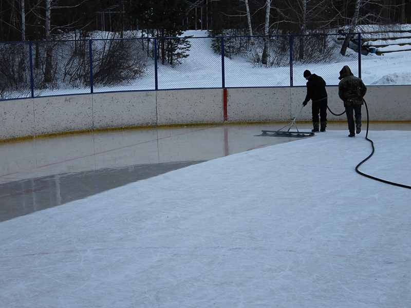 Сотрудники хоккейной базы производят заливку льда на корте, поддерживая его в хорошем состоянии