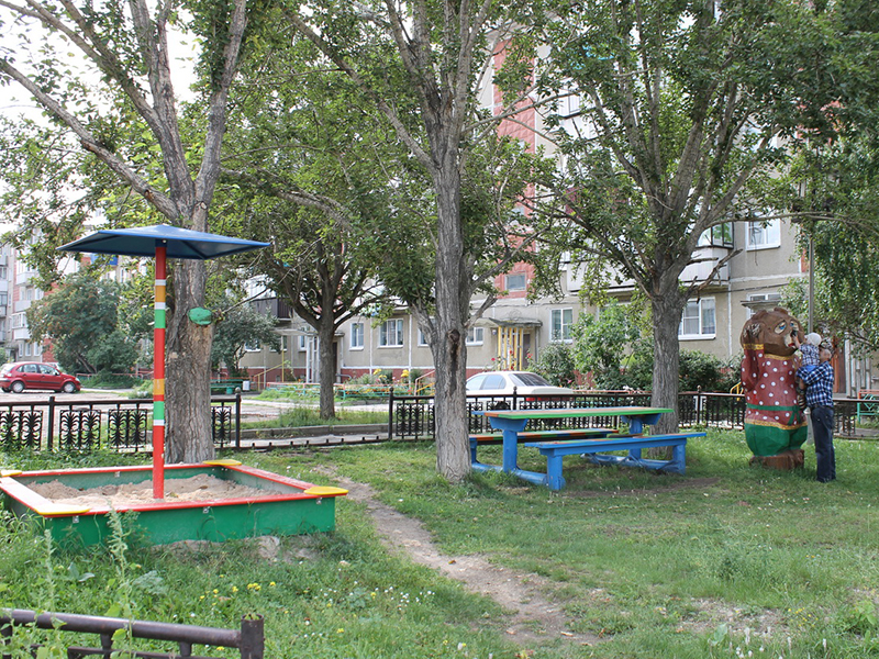 Отгороженная решеткой аккуратная летняя площадка для  прогулок с детьми на улице Лобашова во дворе дома №129